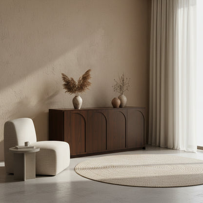 Dark wooden sideboard with decorative items against a wall with an arch-shaped mirror.