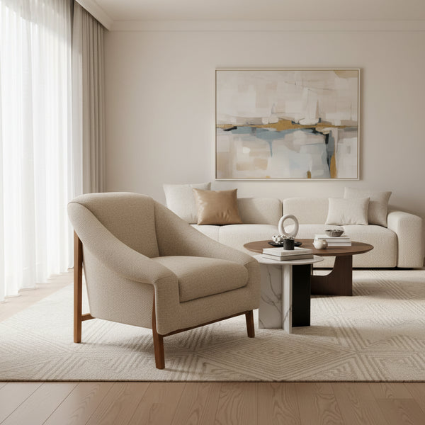 Beige armchair in a room with a wooden side table, lamp, and plant.