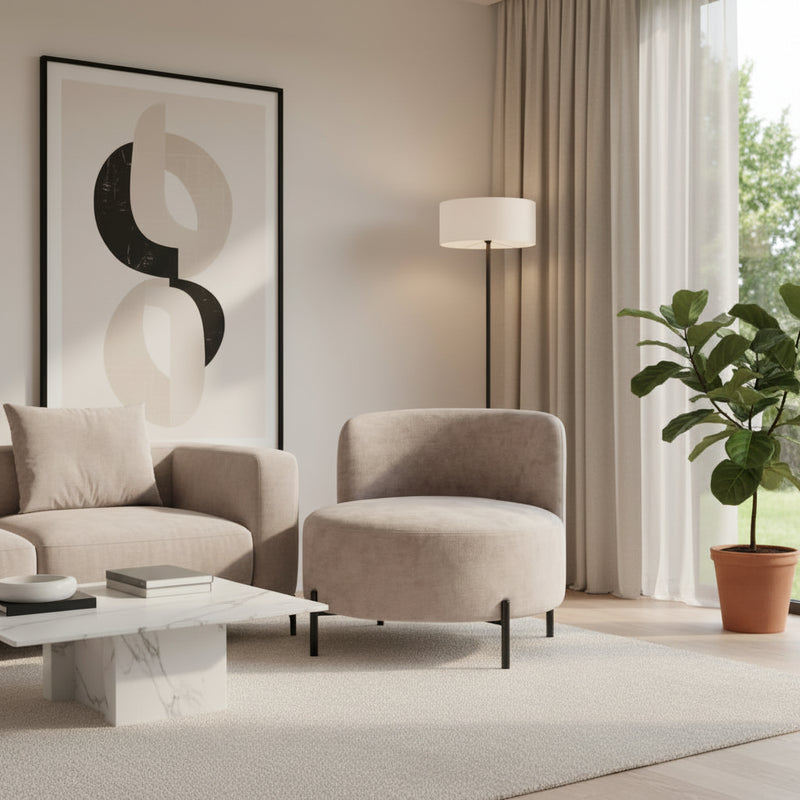 Beige armchair in a living room setting with a lamp and table in the background.