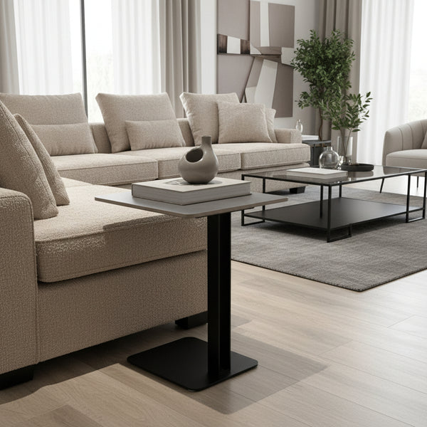 Small gray side table with black base next to a beige sofa on a wooden floor.